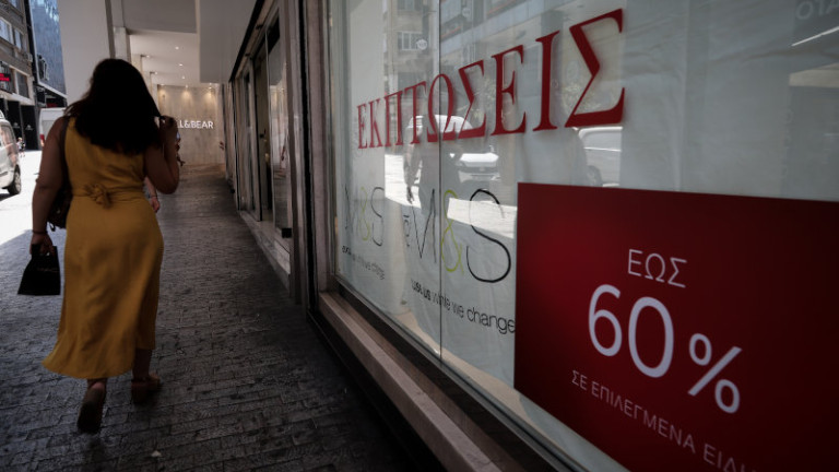 γυναίκα έξω από μαγαζί που κάνει εκπτώσεις