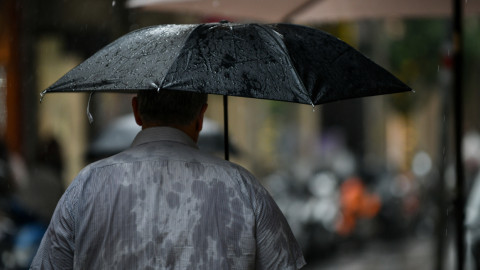 Εικόνα από βροχερό καιρό. Ενας άνδρας κρατά ομπρέλα. 