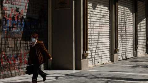 Μια γυναίκα περπατά μπροστά από κλειστά καταστήματα στη Θεσσαλονίκη
