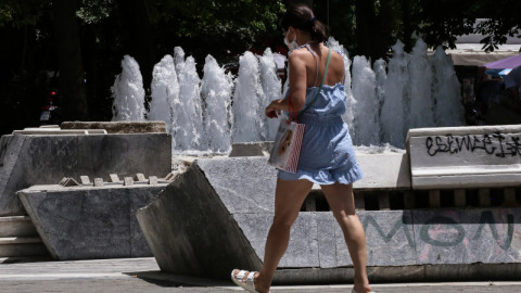 κοπέλα περπατάει κοντά σε συντριβάνι στο κέντρο της Αθήνας