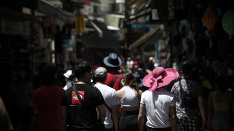 κόσμος με καπέλα περπατάει στο Μοναστηράκι στην Ελλάδα το καλοκαίρι