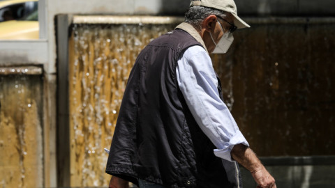 ηλικιωμένος με μάσκα περπατάει κοντά σε συντριβάνι στην Αθήνα