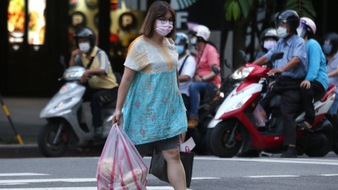 γυναίκα με σακούλες σε δρόμο της Ταϊβάν και πίσω της μηχανάκια