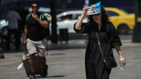 γυναίκα με φυλλάδιο στο κεφάλι περπατάει στο Σύνταγμα