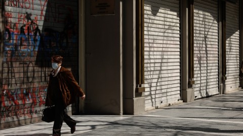 Μια γυναίκα περπατά μπροστά από κλειστά καταστήματα στη Θεσσαλονίκη